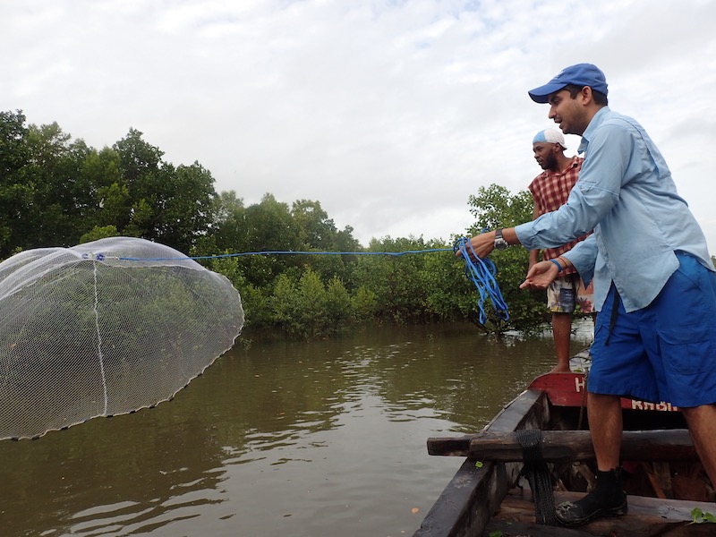 Prosanta Chakrabarty in a boat casting a net into the water