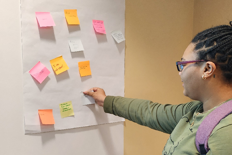 student placing sticky notes on wall