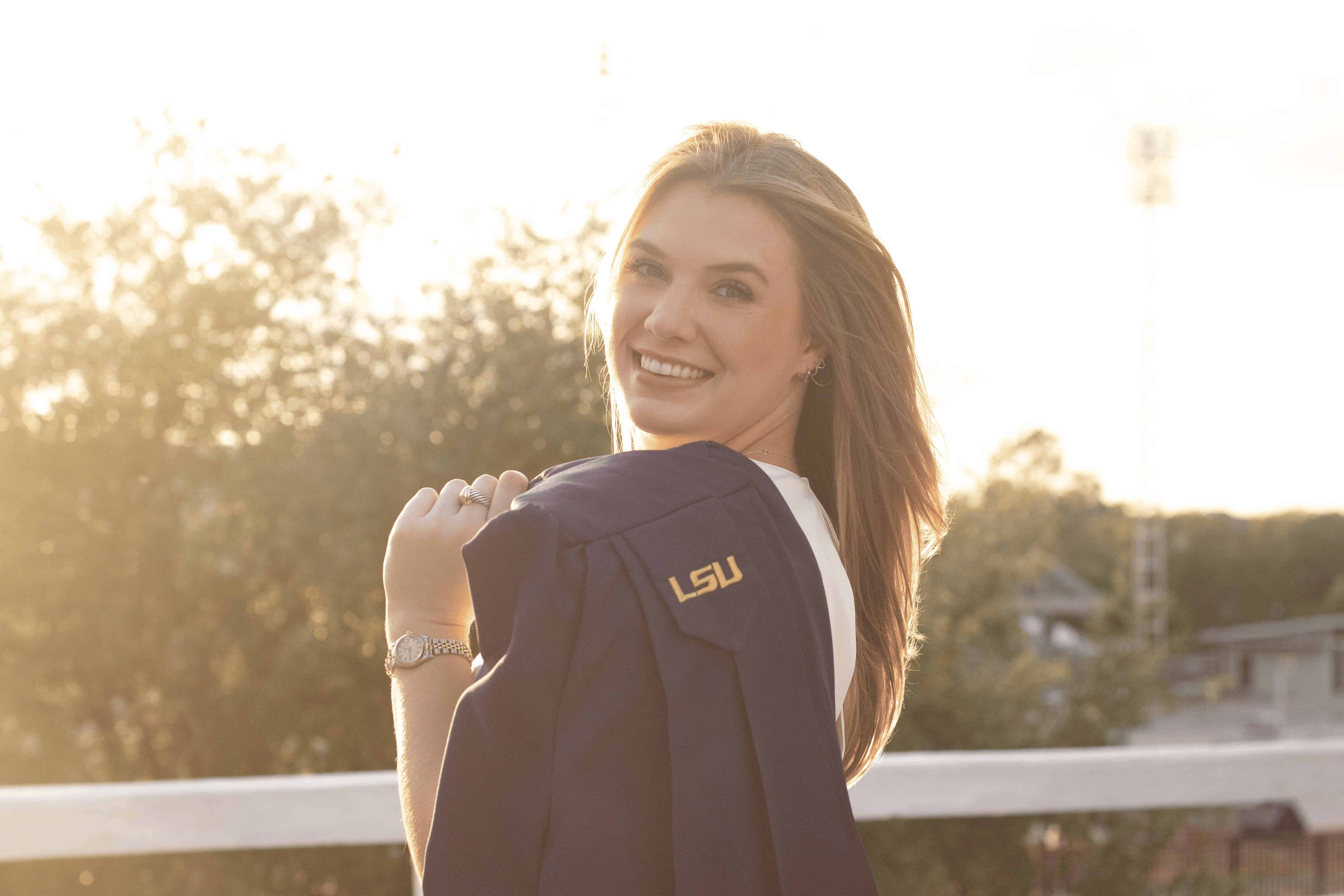 Kaleigh Stallings holding an LSU graduation gown over her shoulder