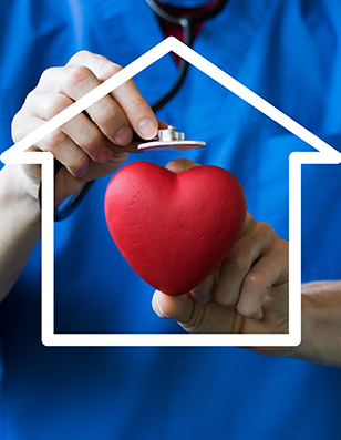 Photo of a medical person dressed in blue scrubs holding a stethoscope over a red heart.